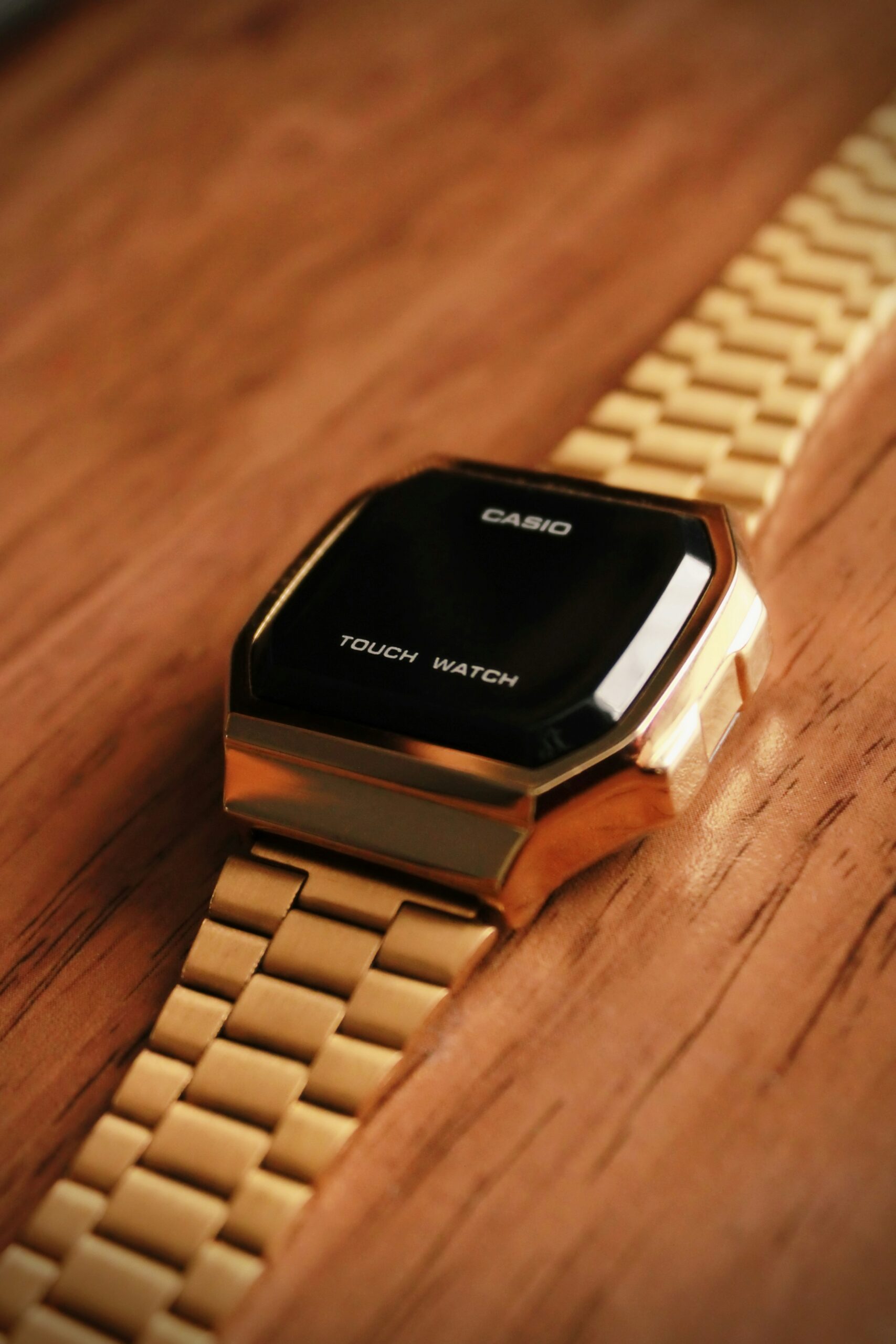 Reloj Casio dorado con pantalla táctil sobre una superficie de madera.
