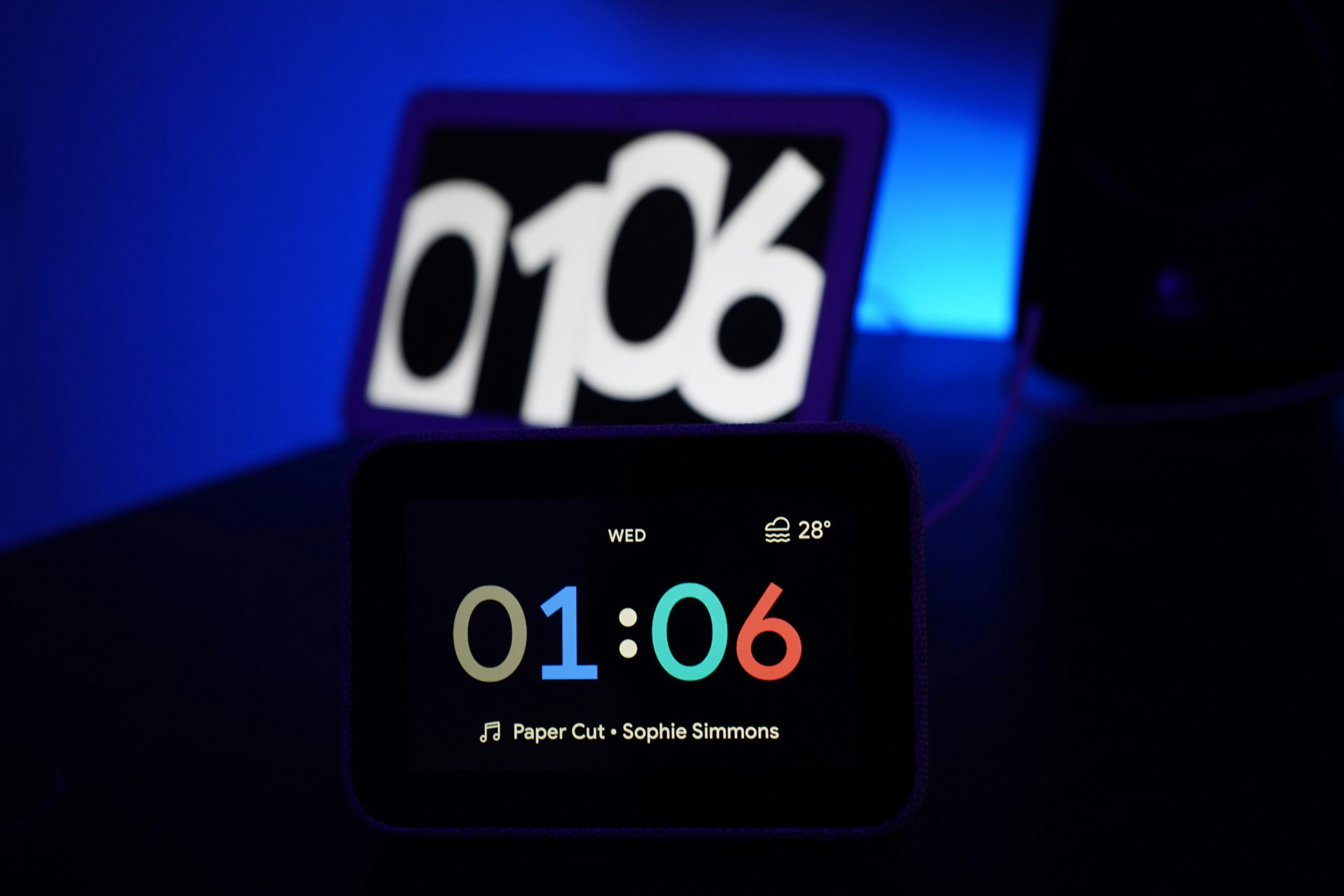 Reloj digital mostrando la hora 01:06, temperatura de 28°C, día miércoles, con música "Paper Cut" de Sophie Simmons.